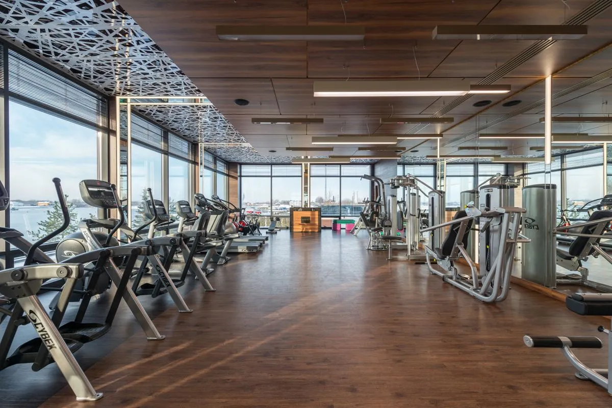 Salão de treino com piso de madeira e aparelhos de musculação